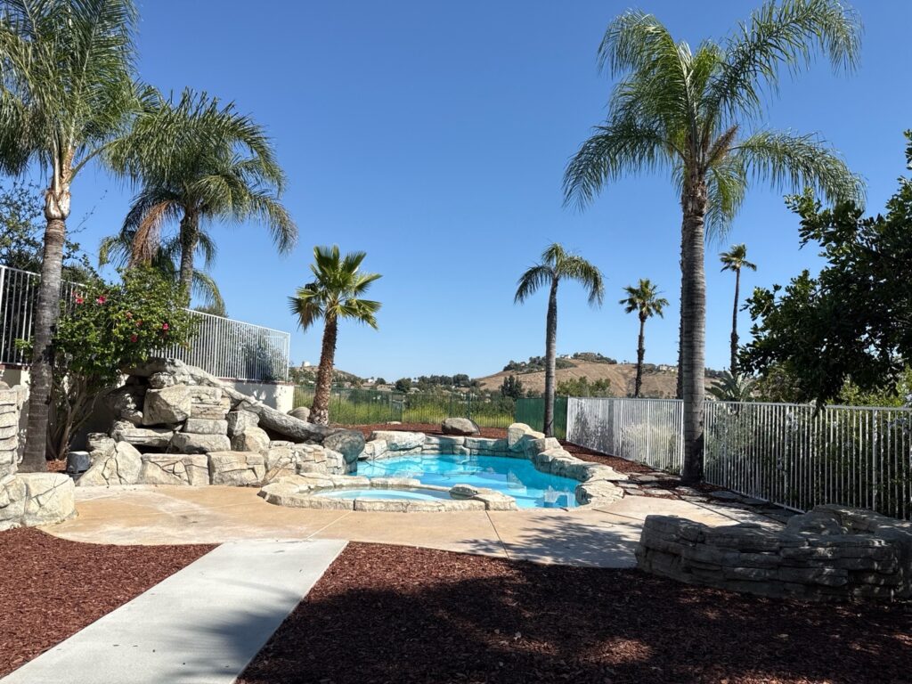 Pool inspection of an in-ground swimming pool with rock waterfall, spa, and safety fence in Southern California